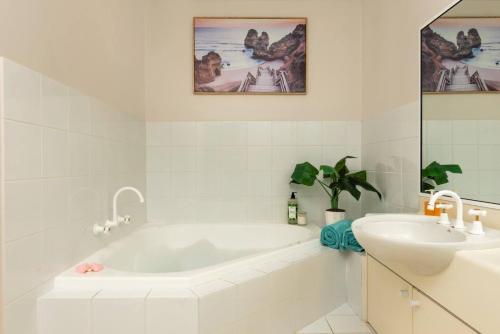 un bagno bianco con vasca e lavandino di Golfers Delight View of 15th hole and Tennis a Mollymook