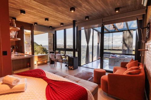 a bedroom with a bed and a living room with windows at Cabana Morada nas Nuvens in Pinto Bandeira
