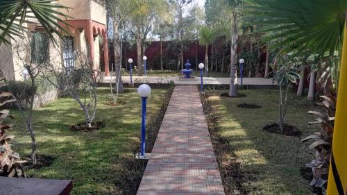 a walkway in a park with palm trees and a building at Villa Tonsi in Sbiti