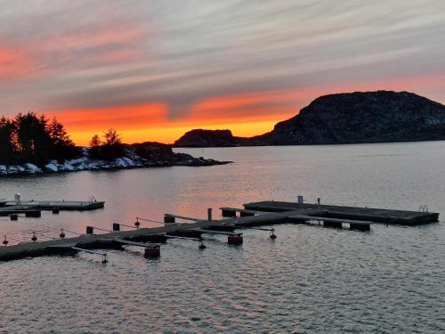 a dock in the water with a sunset in the background at Korshamn in Lyngdal