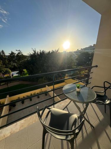 a glass table and chairs on a balcony with the sunset at Ajuda Mar Holidays in Funchal