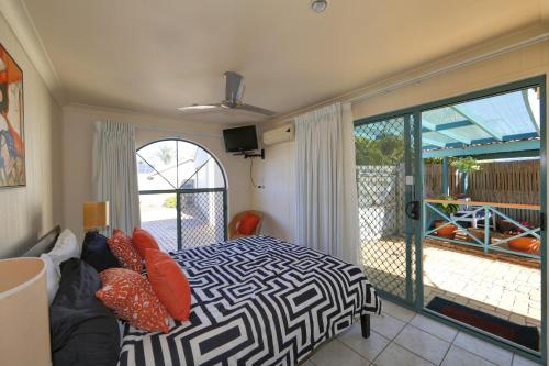 ein Schlafzimmer mit einem Bett und einem Balkon in der Unterkunft Golden Cane Bed & Breakfast in Bargara