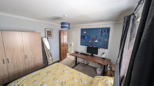 a bedroom with a bed and a desk and a tv at Sydenham Serenity: Bright Home with Conservatory in Belfast