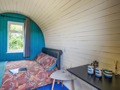 a bedroom with a bed and a table and a window at The Owl Pod - Uk50070 in Welshpool