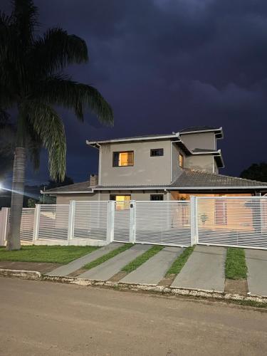 una casa con una recinzione bianca e una palma di Casa das Palmeiras - Charm and Comfort in the Center a Alto Paraíso de Goiás