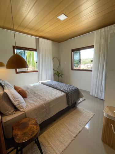 una camera con un grande letto e due finestre di Casa das Palmeiras - Charm and Comfort in the Center a Alto Paraíso de Goiás