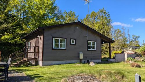 una pequeña casa en un patio con césped en Boats stay play lake cabin, en Broby