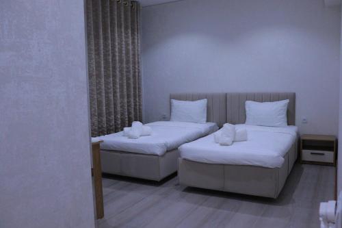 2 bedden in een kamer met witte lakens en kussens bij Intercity Hotel Tashkent by Maskan in Tasjkent