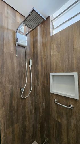 a shower in a bathroom with a wooden wall at Studio reformado e bem equipado in Campinas