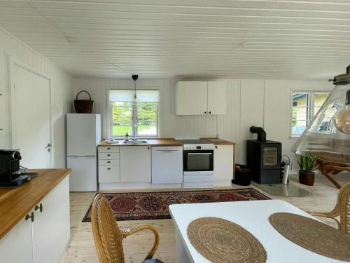 a kitchen with white appliances and a table and chairs at Sommerhus Med Sauna Ved Udsholt Strand in Udsholt Sand