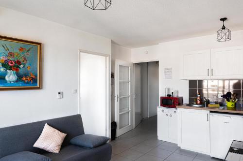 a living room with a couch and a kitchen at Ô Cocon Paisible - WiFi, Calme, Smart TV, Parking - A 2min du Campus TBS in Quint-Fonsegrives