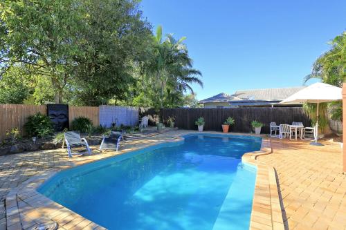 a pool with a pool table and chairs in it at Golden Cane Bed & Breakfast in Bargara