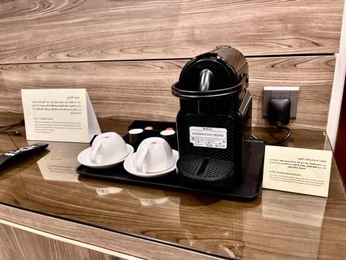 Una cafetera y platos en una bandeja sobre la encimera en Tura Hotel AlNuzha- فندق ترى النزهة, en Riad