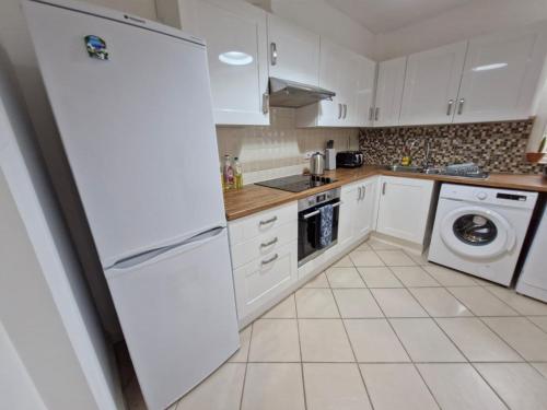 a white kitchen with a refrigerator and a dishwasher at Charming Retreat - Broadstairs Seafront in Broadstairs