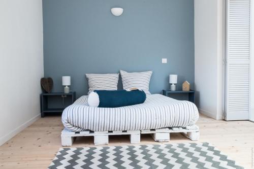 a bedroom with a bed with a blue wall at Loft avec filet d'habitation suspendu géant proche mer in Bouin