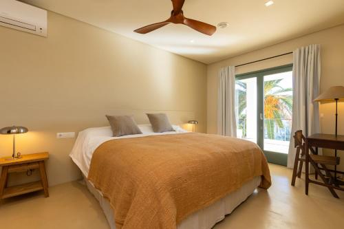 Un dormitorio con una cama y un ventilador de techo. en New Villa Primavera, Mediterranean Calm & Sea view near Mahon, en Mahón