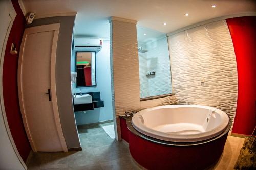 a bathroom with a large tub and a sink at Hotel Motel Paradiso - Carazinho-RS in Caràzinho