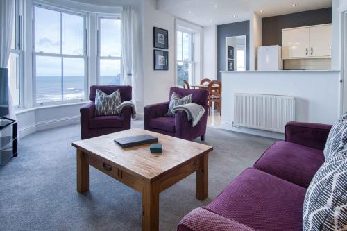 a living room with purple chairs and a coffee table at The Helaina Apartments in Scarborough