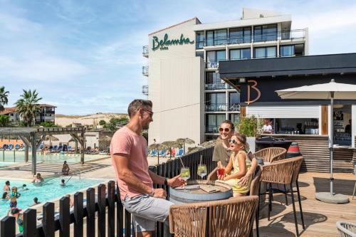 Eine Gruppe von Menschen sitzt am Pool eines Resorts in der Unterkunft Belambra Clubs Seignosse - Les Tuquets in Seignosse