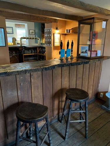 a bar with two wooden stools in a room at Lamb Inn in Wartling