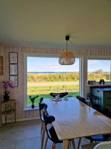 a dining room with a table and a large window at Renovated Beach House With Ocean View in Tjørneholm