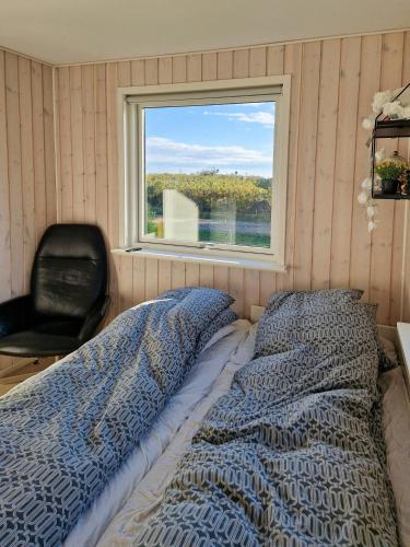 a bedroom with a bed and a chair and a window at Renovated Beach House With Ocean View in Tjørneholm