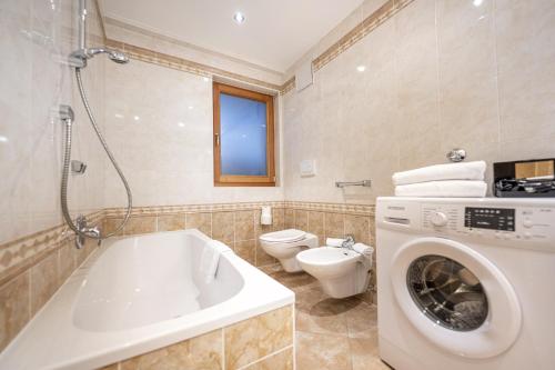 Un baño con lavadora y un inodoro. en Marienstern Apartments, en Santa Cristina Valgardena