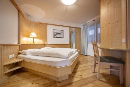 Un dormitorio con una cama, un escritorio y una silla. en Marienstern Apartments, en Santa Cristina Valgardena