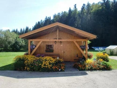 een houten schuur met bloemen ervoor bij Ferienhaus In Röhrnbach Mit Grill Und Terrasse in Röhrnbach