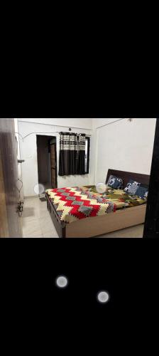 a bedroom with a bed with a comforter on it at Gurukrupa Home stay in Rājpīpla