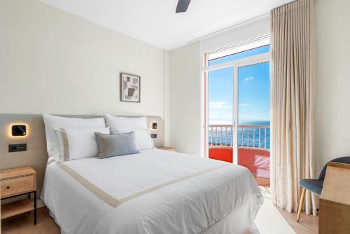 une chambre blanche avec un lit et une grande fenêtre dans l'établissement Dúplex de Lujo Frente al Mar Terraza en Radazul, à Radazul