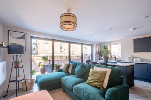 a living room with a blue couch and a kitchen at Luxury 4BDR House By Torr Property Group Contractors Accommodation With Free Gated Secure Parking & Private Patio Garden Liverpool in Liverpool