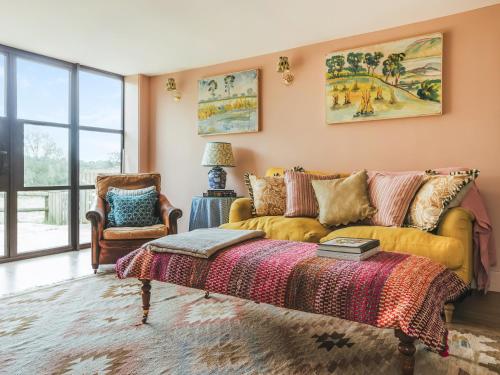 a living room with a yellow couch and a chair at The Shearing Shed in Peasmarsh