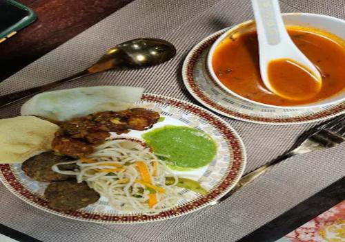 Un plato de comida con fideos y un tazón de sopa. en Vasant Kunj Nature Resort, en Rāma