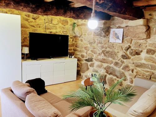 a living room with a tv on a stone wall at Casa do Terrado in Tourém