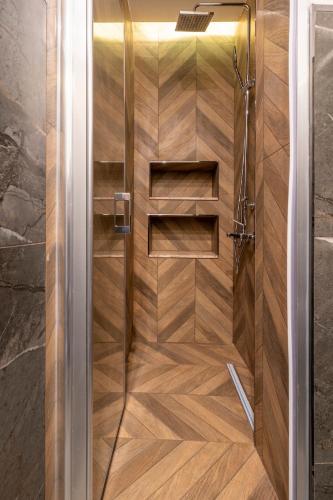a shower with a wooden floor and a glass door at Stone studio just a 3min walk from the Clock Tower in Konak