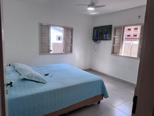 1 Schlafzimmer mit einem Bett mit blauer Bettwäsche und 2 Fenstern in der Unterkunft Casa Férias Xero in Capitólio