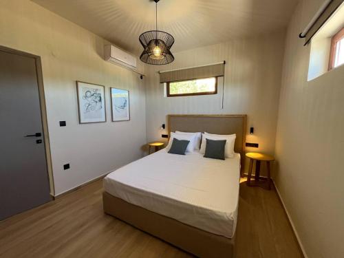 een slaapkamer met een bed met 2 tafels en een raam bij SeaWave Villas, By Hellocrete in Chania