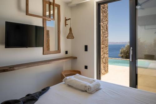 a bedroom with a bed with a view of the ocean at ArtOikia Luxury Villas, By Hellocrete in Saktoúria
