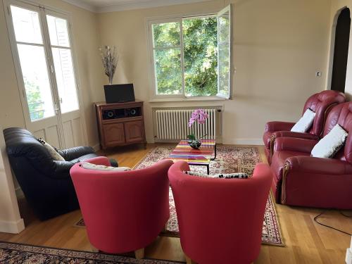 a living room with red chairs and a table at Adélaide Cottage in Chevagny-les-Chevrières