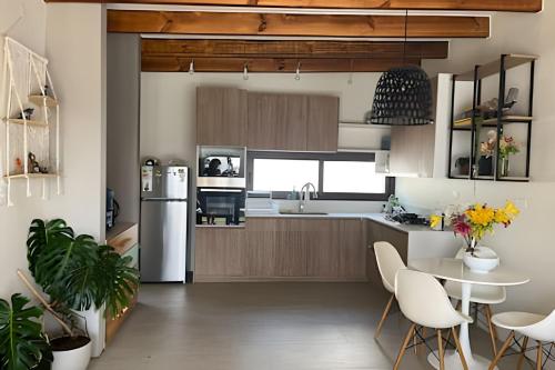 Il comprend une cuisine équipée d'un réfrigérateur, d'une table et de chaises. dans l'établissement Casa amplia y moderna en Cerro Tacna, Maitencillo, à Maitencillo