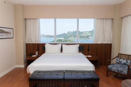 a bedroom with a large bed and a window at Golden Tulip Porto Vitória in Vitória