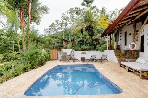 Una piscina en un patio con sillas y una casa. en Paradiselodge - Poolvilla, en Platanillo