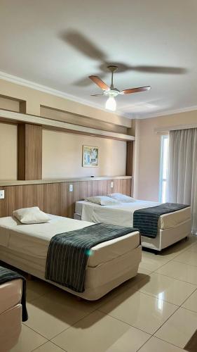 ein Schlafzimmer mit zwei Betten und einem Deckenventilator in der Unterkunft Hotel Lux in Poços de Caldas