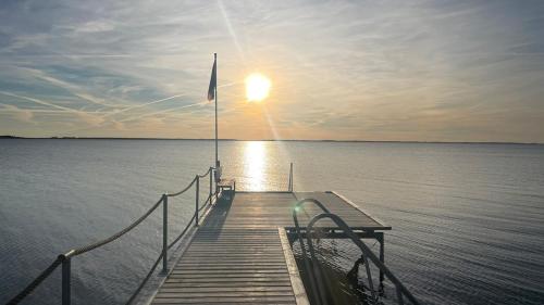 un quai avec un coucher de soleil sur l'eau dans l'établissement Cozy cottage near beach and nature, à Martofte