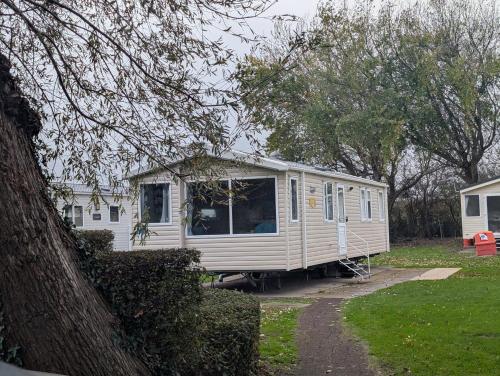 a white caravan parked in a yard next to a tree at Family Friendly Caravan in Burnham on Sea in Burnham on Sea