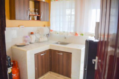 a small kitchen with a sink and a refrigerator at Deluxe Stays in Nakuru