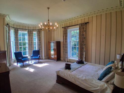 a bedroom with a bed and two chairs and a chandelier at Hillside House in Saline