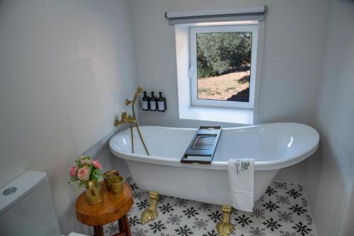 ein Bad mit einer weißen Badewanne und einem Fenster in der Unterkunft Villa Jerusalém - Casa de Campo in Avantos