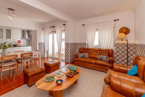 a living room with leather furniture and a table at Moradia São João-Spacious Beachfront Villa in A dos Cunhados